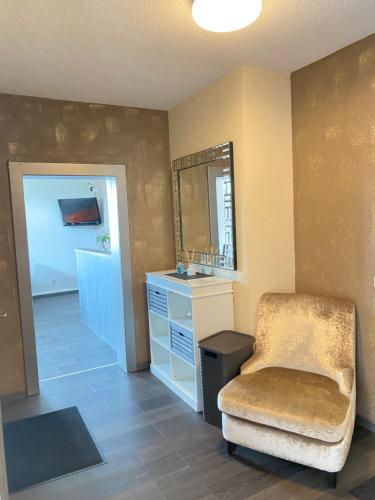 uma casa de banho com uma cadeira, um lavatório e um espelho. em Blue Max Parkzimmer em Grossenhain