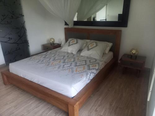 um quarto com uma cama com lençóis brancos e um espelho em Bungalow de charme em Capesterre-Belle-Eau