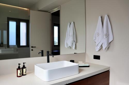 een badkamer met een witte wastafel en een spiegel bij Amphitheatro Boutique Hotel in Meganisi