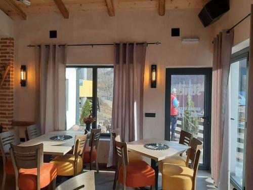 a dining room with two tables and chairs and a person at Apartmani Sunce Stara planina in Crni Vrh