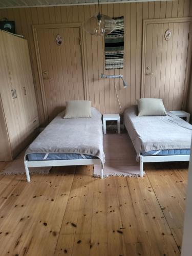 two beds in a room with wooden floors at Sahlin - Ängelholm in Ängelholm