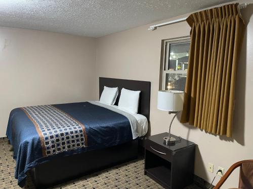 a hotel room with a bed and a window at Economy Inn & Suites in Ashtabula