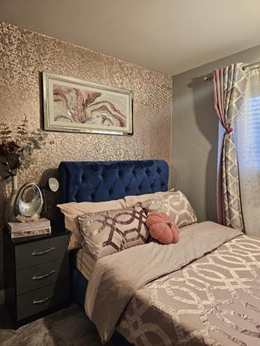 a bed with a blue headboard in a bedroom at Angle’s Nest in Whitchurch