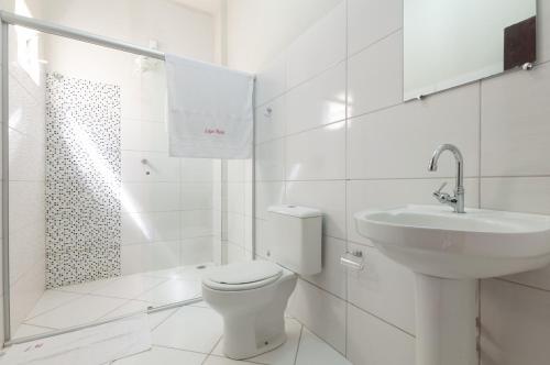 a white bathroom with a toilet and a sink at Lapa Hotel in Bom Jesus da Lapa