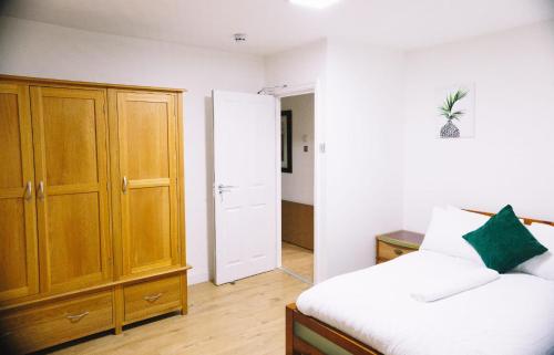 a bedroom with a bed and a wooden cabinet at 6 bedroom property in Sidcup