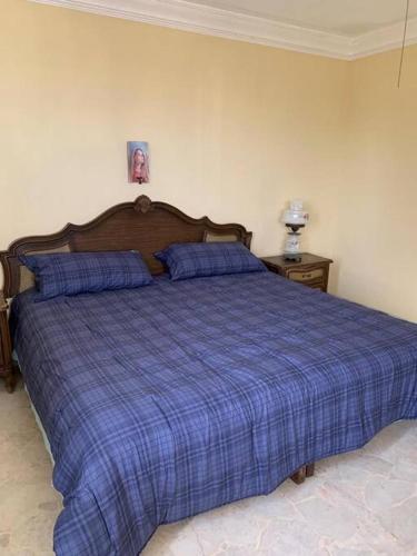 a bed in a bedroom with a blue plaid blanket at La casa del cerro con vista al oceano pacifico in Mazatlán