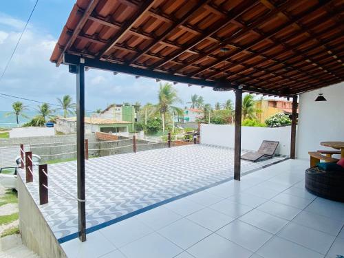 an outdoor patio with a roof with a view of the ocean at Casa de praia Enseadas do corais - 20 metros da praia in Cabo de Santo Agostinho