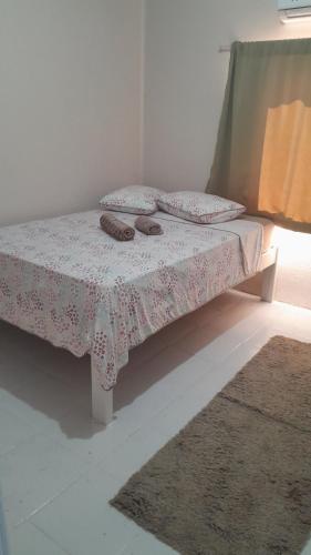 ein Bett in einem Zimmer mit zwei Hausschuhen darauf in der Unterkunft Quartos em Ametista do Sul in Ametista do Sul
