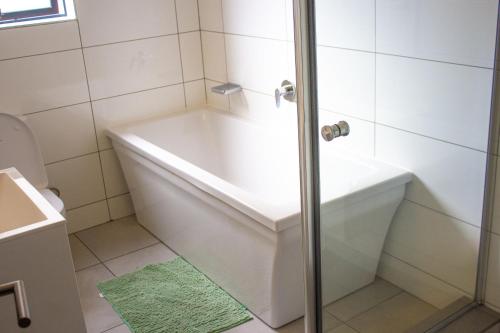 een badkamer met een wit bad en een douche bij 13 Elizabeth Place - Luxury Apartments, Free Wi-Fi in Midrand