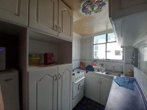 a kitchen with white cabinets and a stove top oven at Departamento Amoblado en Quito Norte, sector la Udla Universidad Av Granados in Quito