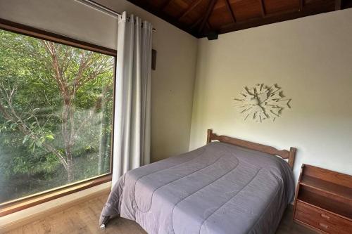 a bedroom with a bed and a large window at Chalé Canto da Montanha in Serra do Cipo