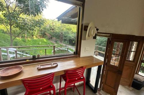 a table with two red chairs and a large window at Chalé Canto da Montanha in Serra do Cipo