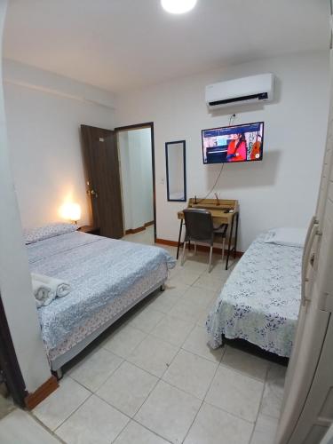 1 dormitorio con 2 camas y escritorio con TV en Habitación confortable y central a 100mts de la playa, en San Andrés