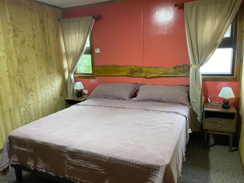 a bedroom with a large bed with red walls at Hostal Rama Fueguina in Teodoro Schmidt