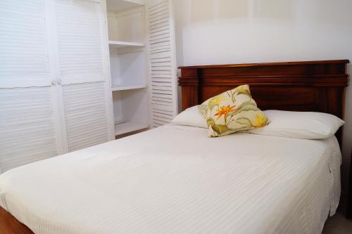 uma cama branca com uma cabeceira em madeira e uma almofada em Casita Marlín Quepos em Quepos
