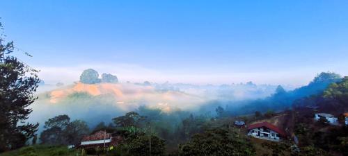 a misty valley with houses on a hill with trees at Cabaña Starka & Jacuzzi in Marinilla