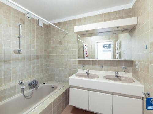 uma casa de banho com 2 lavatórios, uma banheira e um espelho. em Blomme 0103 Apartment on the seafront em De Haan