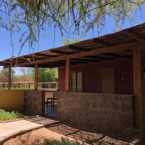 a wooden pavilion with a table and a fence at Cabañas el Chañar in San Pedro de Atacama