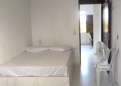 a small white bedroom with a bed and a chair at Hostel Summer Praia do Sol in João Pessoa