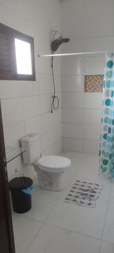 a white bathroom with a toilet and a window at Hostel Summer Praia do Sol in João Pessoa