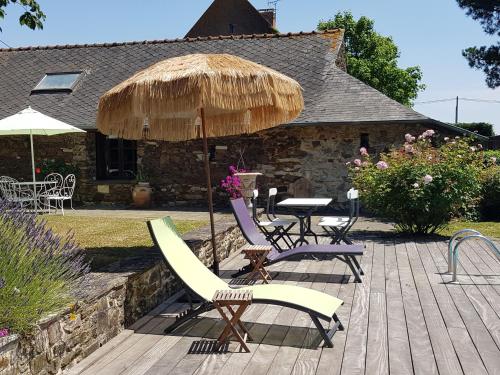 a patio with a table and chairs and an umbrella at Havre de paix avec piscine chauffée, jardin arboré et activités pour tous - FR-1-306-1142 in Teillé
