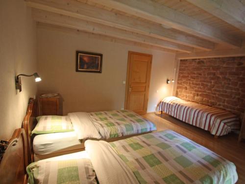 een slaapkamer met 2 bedden en een bakstenen muur bij Gîte Taintrux, 5 pièces, 10 personnes - FR-1-589-232 in Taintrux