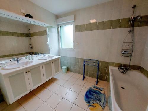 a bathroom with two sinks and a tub and a mirror at Gîte Saint-Mars-sur-la-Futaie, 4 pièces, 6 personnes - FR-1-600-94 in Saint-Mars-sur-la-Futaie