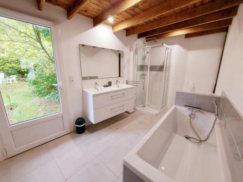 ein Badezimmer mit einer Badewanne, einem Waschbecken und einem Spiegel in der Unterkunft Gîte Saint-Poix, 5 pièces, 11 personnes - FR-1-600-212 