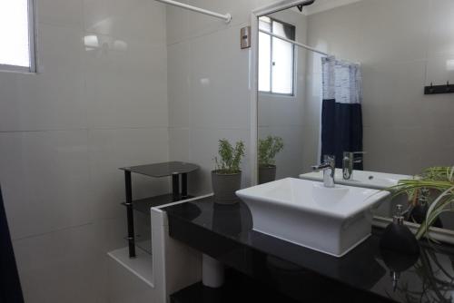 a bathroom with a white sink and a black counter at Casa CasCal in Santiago