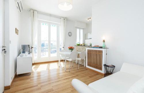 Cette chambre blanche dispose d'une cuisine, d'une table et de chaises. dans l'établissement Deux pièces terrasse sous les étoiles, à Nice