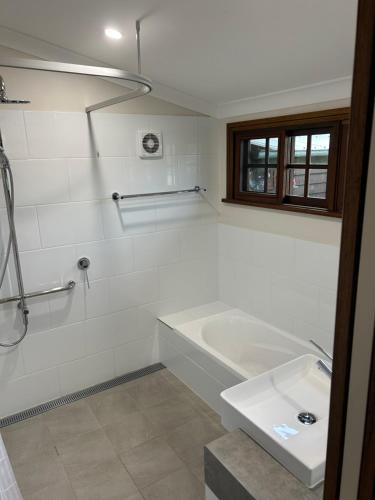 Baño blanco con bañera y lavamanos en Forest Lodge Highfields, en Cawdor