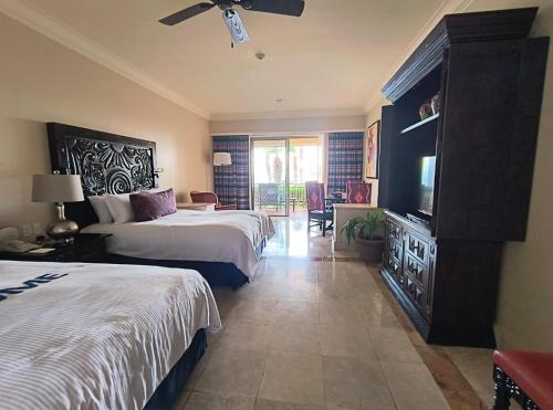 a hotel room with two beds and a television at Paraíso Escondido in Cabo San Lucas