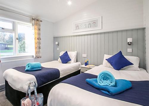 Swanage Coastal Park في سواناج: سريرين في غرفة عليها وسائد زرقاء