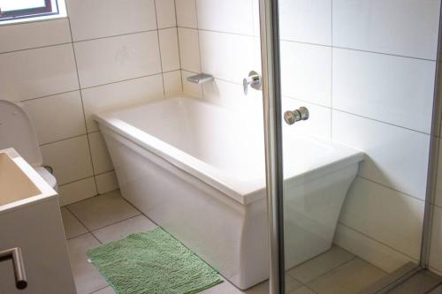 a white bath tub in a bathroom with a green rug at 11 Elizabeth Place - Luxury Apartments, Free Wi-Fi in Midrand