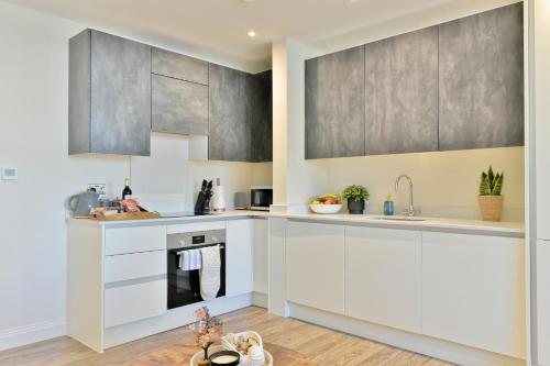una cocina con armarios blancos y electrodomésticos de acero inoxidable en Stunning apartment near citycentre & Oracle, en Reading