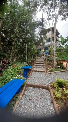 a garden with blue benches and a house at Kitnet em meio à mata Atlântica in Juquitiba