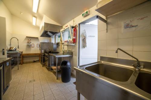 een keuken met een grote roestvrijstalen wastafel bij GITE DES 3 ETANGS in Malvières