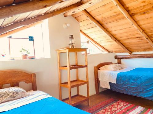 two beds in a room with wooden ceilings at Cabaña del viajero. in Ollantaytambo