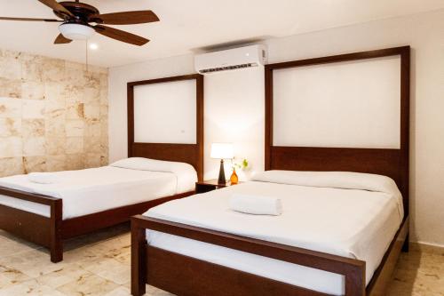 a bedroom with two beds and a ceiling fan at La Aurora Hotel Colonial in Valladolid