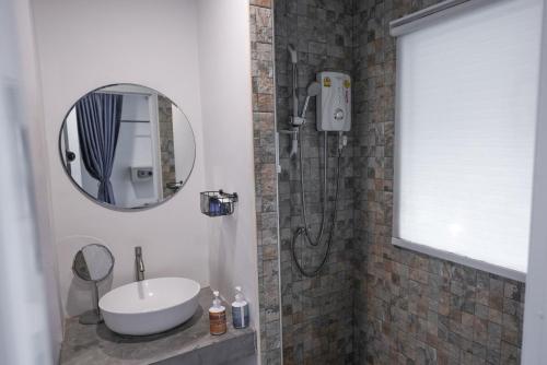 a bathroom with a sink and a shower with a mirror at KRAAM Silhouette Hotel & Cafe Phuket in Ban Kata
