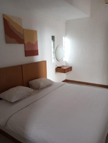 ein großes weißes Bett in einem Zimmer mit Spiegel in der Unterkunft Amelle Villas & Residences Canggu in Canggu