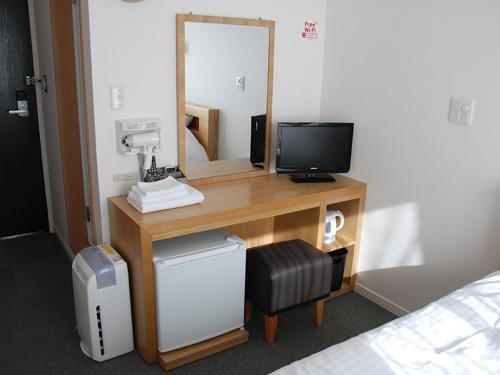 a desk with a television and a mirror in a room at ビジネスホテル 山手INN in Iidamachi
