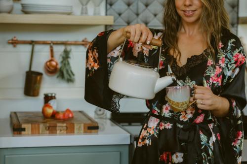 a woman in a kitchen preparing a cup of coffee at Award-winning A-frame Chalet W Cedar Tub & Views in Julian