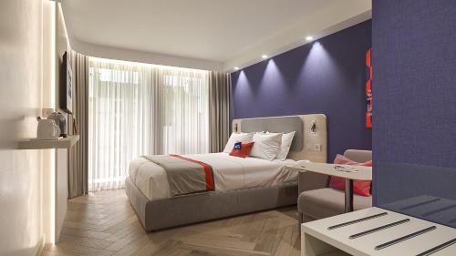 um quarto com uma cama e uma parede roxa em Holiday Inn Express Porto - Boavista, an IHG Hotel no Porto