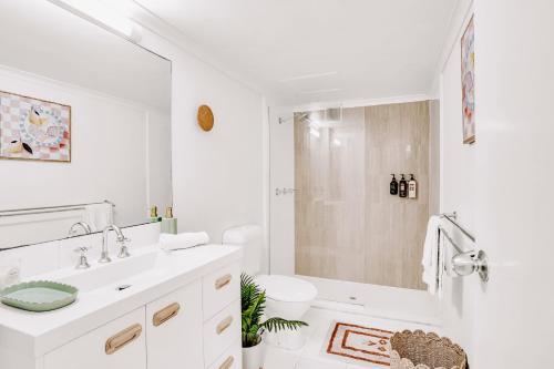 a white bathroom with a sink and a shower at Beachfront Beauty in Alexandra Headland