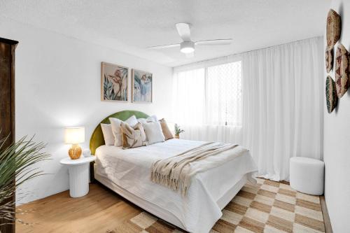 a white bedroom with a bed and a window at Beachfront Beauty in Alexandra Headland