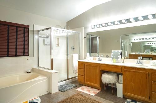 La salle de bains est pourvue d'une baignoire, d'un lavabo et d'une douche. dans l'établissement 5BR 3BA Family friendly entire home w pool, spa, games, tvs, and more, à Las Vegas