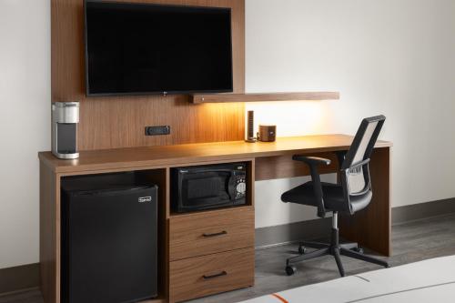 a computer desk with a tv and a chair at La Quinta Inn & Suites by Wyndham Williston Burlington in Williston