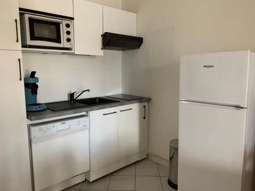 La cuisine est équipée d'un réfrigérateur blanc et d'un four micro-ondes. dans l'établissement Charmant T2 à 2 pas de la plage avec terrasses, parking et local vélo – 5 pers, ménage inclus - FR-1-319-435, à Biscarrosse