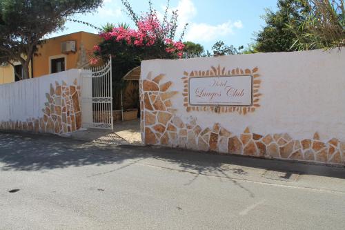 a white fence with a gate with a sign on it at Luagos club Resort in Lampedusa